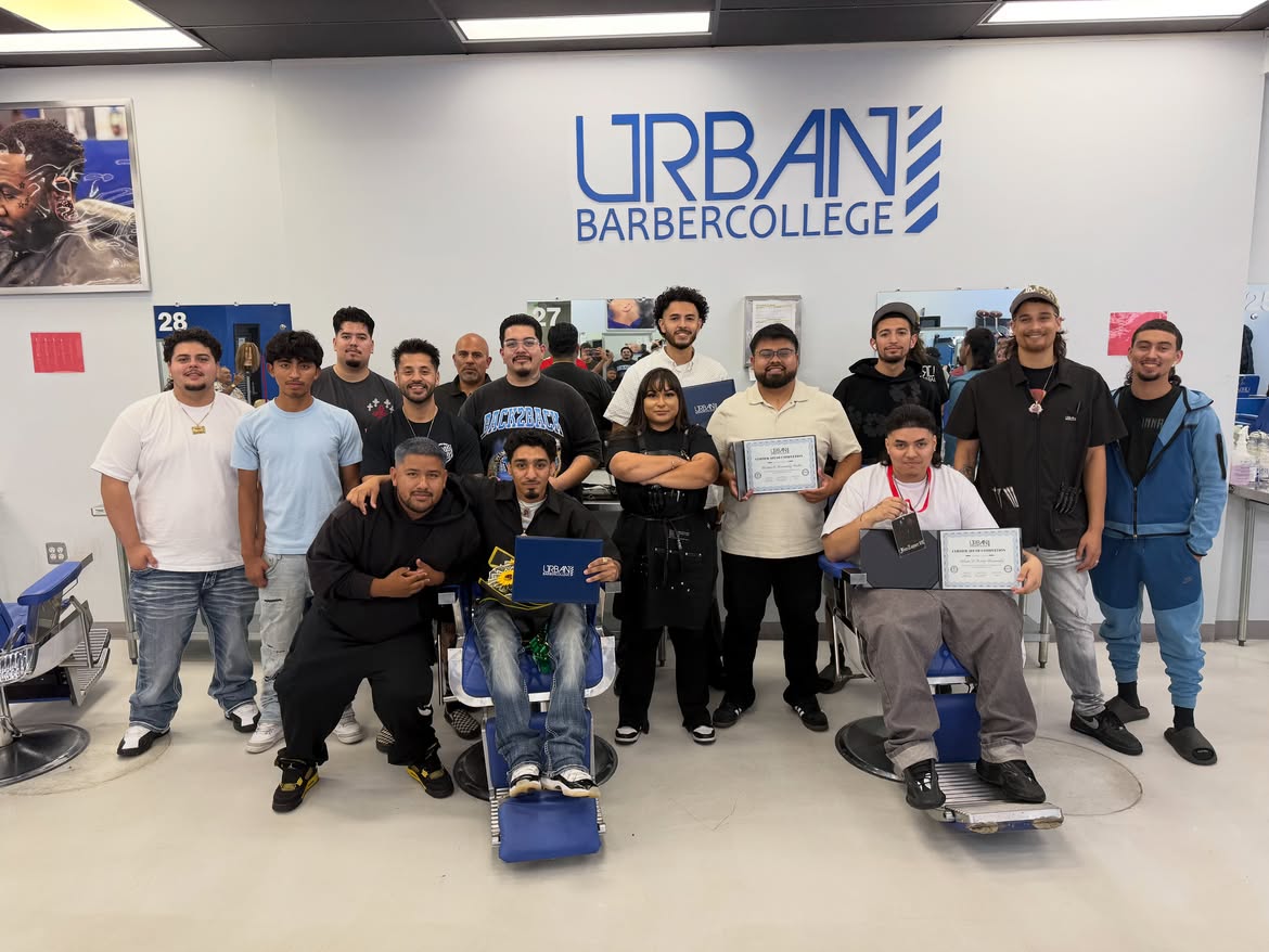 A group of Urban Barber College graduates at the Concord campus, posing with their certificates of completion